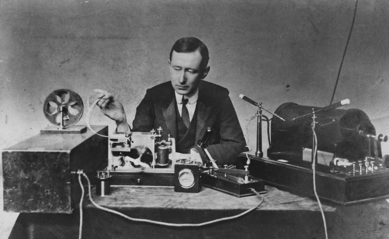 Guglielmo Marconi seated at a table of early wireless telegraph apparatus