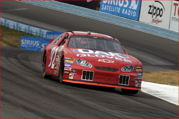 A stock car at speed on a road course