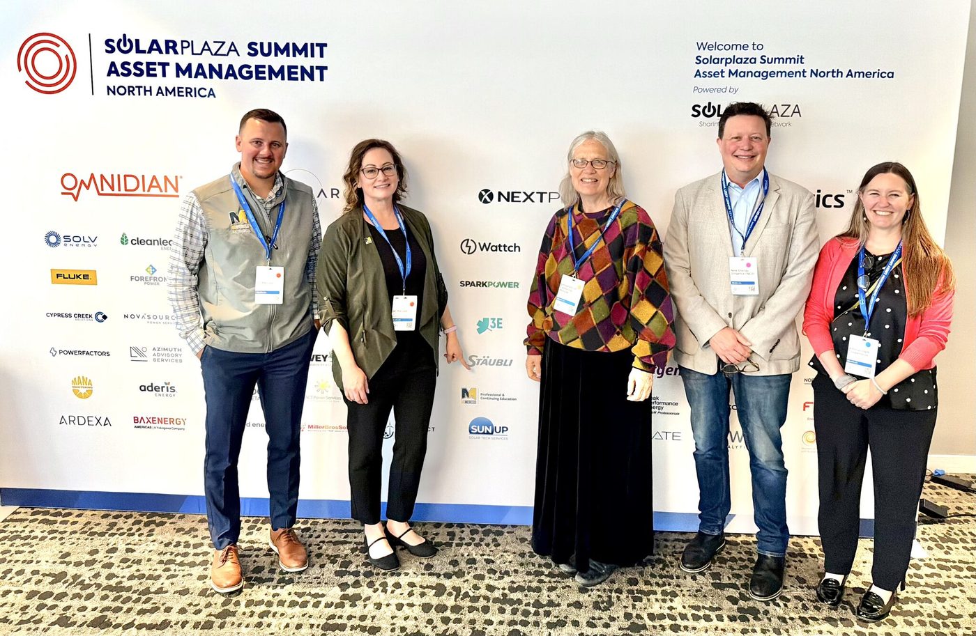 Five attendees in front of the Solarplaza Summit Asset Management North America backdrop in San Diego