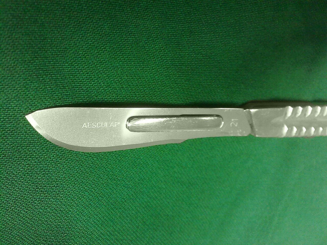 A surgical scalpel on a green surgical drape